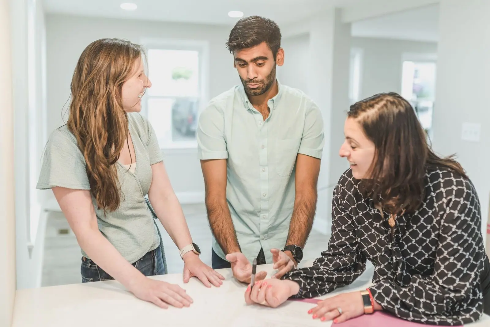 A homebuyer couple and property adviser discuss the paperwork; illustrative stock image, not an Abhipra client or endorsement