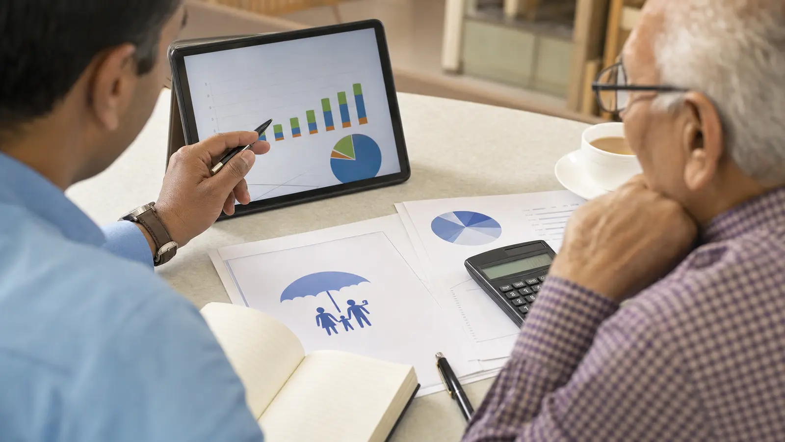 An adviser and senior investor comparing pension-income options on an office desk.